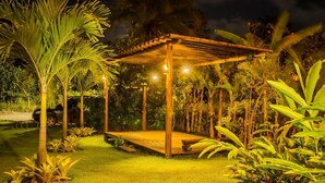 A wooden pergola structure with a platform, surrounded by lush greenery and palm trees. - Pousada Apoema (Maraú)