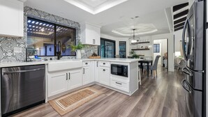 A modern kitchen with white cabinetry, a built-in microwave, and a stainless steel dishwasher.