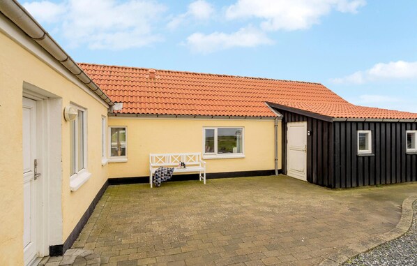 Stylish home with a red-tiled roof, white door, and a window offering a view.