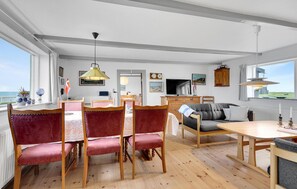 Relax in this spacious living area with a dining table, comfortable sofa, and large windows offering a view of the outdoors.