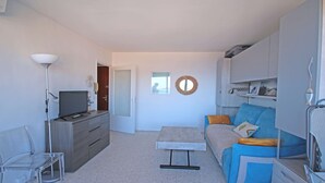 Un salon moderne avec un téléviseur à écran plat, un canapé, une table basse et une lampe.