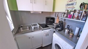 Une cuisine compacte équipée d’un évier, d’un grille-pain, d’une bouilloire et d’un lave-linge.