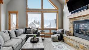 Una sala de estar acogedora con un amplio sofá modular, una chimenea y un televisor montado en la pared.