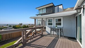 Une maison moderne dotée d’une terrasse en bois, d’un balcon et offrant une vue sur l’océan.
