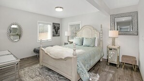 Une chambre à coucher avec un lit à baldaquin, un miroir, des tables de chevet et un tapis.