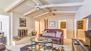 A cozy living room with a fireplace, leather sofa, and a glass coffee table.