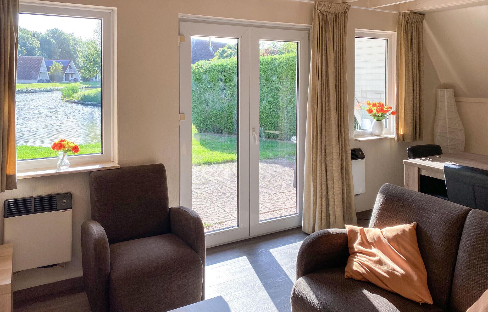 Una habitación con sofá, una silla, una mesa y vistas a un jardín a través de una puerta corrediza.