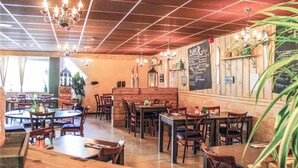 Un restaurante acogedor con mesas y sillas de madera, un menú en una pizarra y luces colgantes.