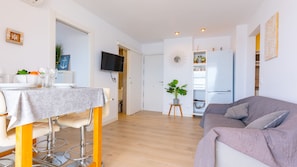 En moderne lejlighed med spiseplads, opholdsstue, køkken og tv.