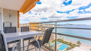 A balcony with a table and chairs, a view of the sea, and a pool area. - 11F 2 Dormitorios con Vistas al mar (Calp)