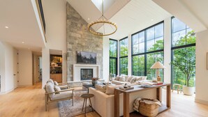 Un salón amplio con chimenea, ventanas grandes y un techo alto.