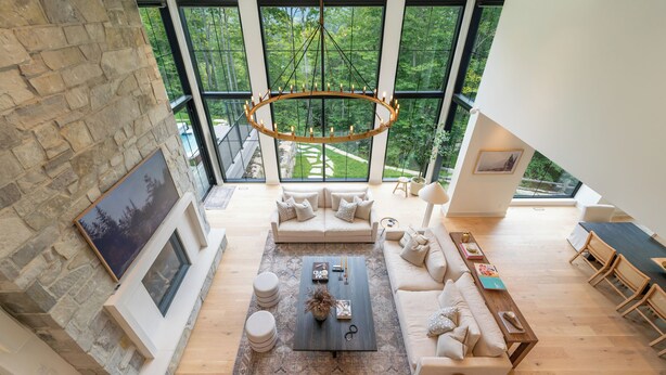 Un salón amplio con un gran ventanal, chimenea y una lámpara moderna.