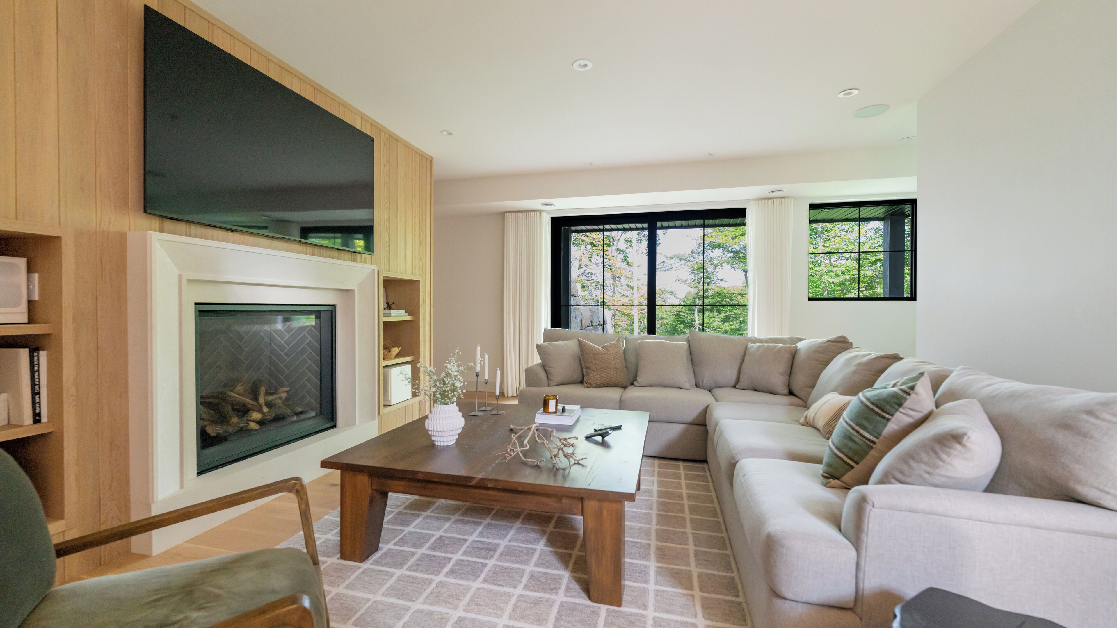 A modern living room with a fireplace, a large window, and a sectional sofa.