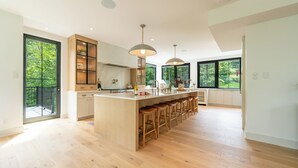 Una cocina moderna con una isla grande, taburetes de bar y vistas a zonas verdes.