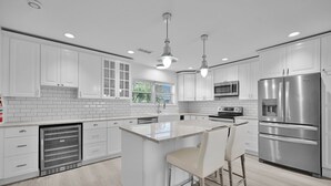 A modern kitchen with white cabinets, stainless steel appliances, and a central island with bar stools. - 2260 Managed By Brampton Park (Pompano Beach)