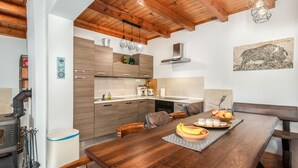 Eine moderne Küche mit Holzschränken, einem mit Früchten gedeckten Esstisch und einer rustikalen Decke.