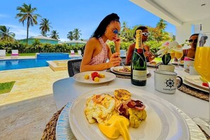 Una mesa de comedor con platos de desayuno, una botella de champán Moët & Chandon y una taza con el logo de un timón.
