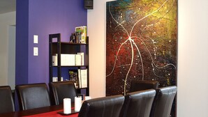 A conference room with a red table, black leather chairs, a bookshelf, and a large abstract painting. - La Maison jaune: Spa, comfort, wifi (Chute-Saint-Philippe)