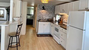 A compact kitchen with white cabinetry, a central island, and a patterned backsplash. - Cozy retreat, near some of the best Florida beaches! (Bradenton)