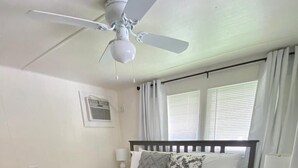 A bedroom with a bed, a ceiling fan, a window with curtains, and a bedside table with a lamp. - Cozy retreat, near some of the best Florida beaches! (Bradenton)