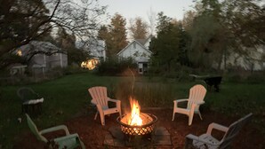 Een vuurkorf met vier Adirondack stoelen eromheen, in een achtertuin.
