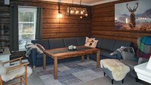 Een gezellige woonkamer met een houten wand, een bank, een salontafel en een schilderij van een hert.