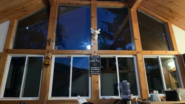 A wooden cabin with large windows and a sign reading "Welcome to Fire Pit." - Beautiful, private home with fire pit and river access! (Bath)