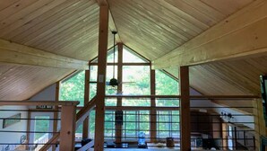 A wooden interior with a high ceiling, large windows, and a staircase. - Beautiful, private home with fire pit and river access! (Bath)