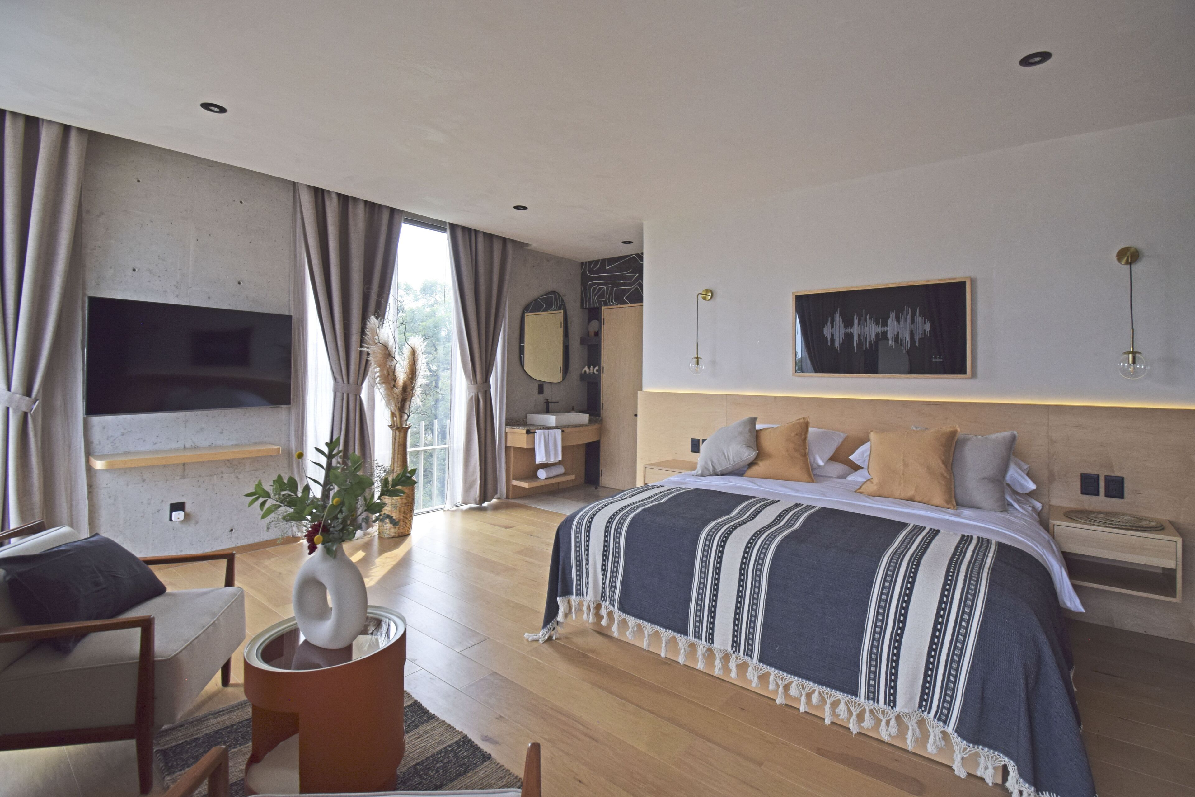 A modern bedroom with a large bed, a TV, a bedside table, and a window with curtains.