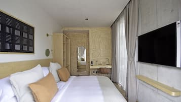 Une chambre d’hôtel avec un grand lit, une télévision, un miroir et une salle de bain visible à travers une porte ouverte.