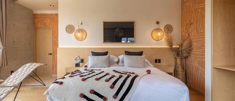 Un dormitorio moderno con una cama grande, un televisor montado en la pared y un panel decorativo.