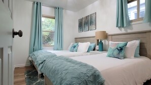 Une chambre à coucher avec un grand lit, une fenêtre avec des rideaux, une lampe de chevet et un luminaire au plafond.