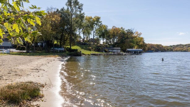 Une vue sur le lac, avec une plage de sable, un quai et des maisons en arrière-plan.