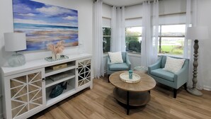 Un salon moderne agrémenté d’un grand tableau, de deux fauteuils, d’une table basse et d’un meuble console blanc doté d’étagères.