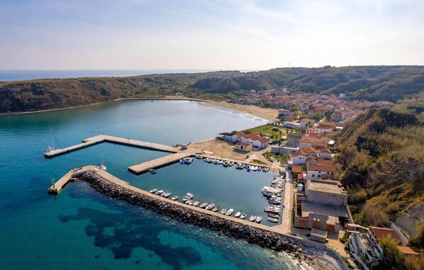 Enjoy scenic views of the coastline from this hillside town, surrounded by lush greenery and a marina with clear blue waters.