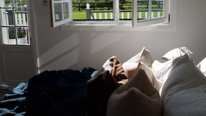 Un dormitorio con un ventanal grande, una cama y vistas a un paisaje verde.