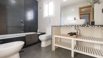 Een bad/douchecombinatie, een haardroger, een bidet, handdoeken