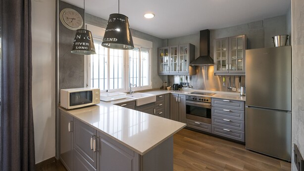 Una cocina moderna con una isla central, electrodomésticos de acero inoxidable y un amplio ventanal.
