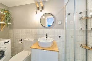 Une salle de bain équipée d’un lavabo, de toilettes et d’un lave-linge.