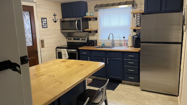 A compact kitchen with a wooden table, a sink, and a refrigerator. - Lexington Stays. Close to town and beach!  (Lexington)