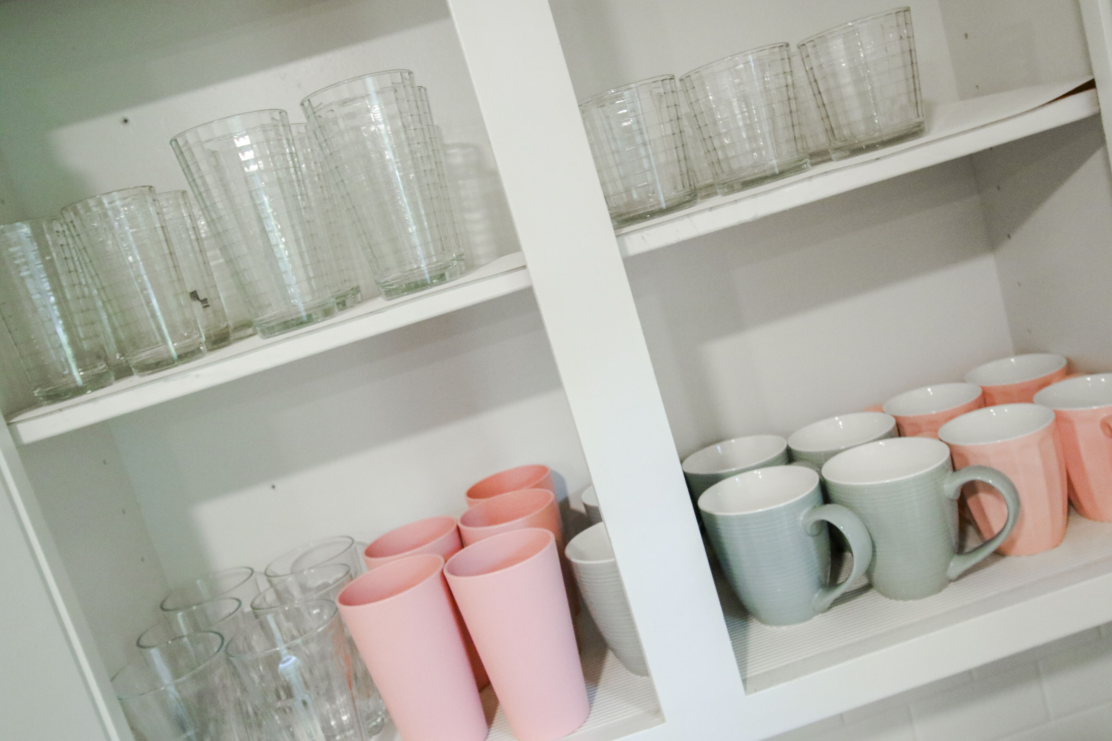 Une étagère avec des verres à boire transparents et des tasses en céramique.