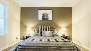 A bedroom with a large bed, two bedside lamps, a ceiling light, and a bull-themed artwork on the wall. - The Ravine • Hot Tub Forest Escape, Epic Gameroom, Fast WIFI & Pet Friendly (Basye)
