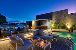 A rooftop bar with outdoor seating, a pool, and a view of the city at dusk. - The Almin Hotel (Hong Gai)