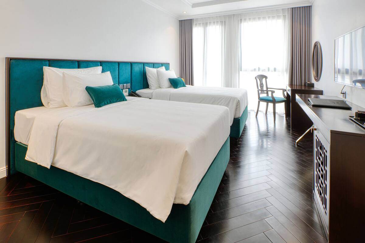 A hotel room with two beds, a desk, and a chair.