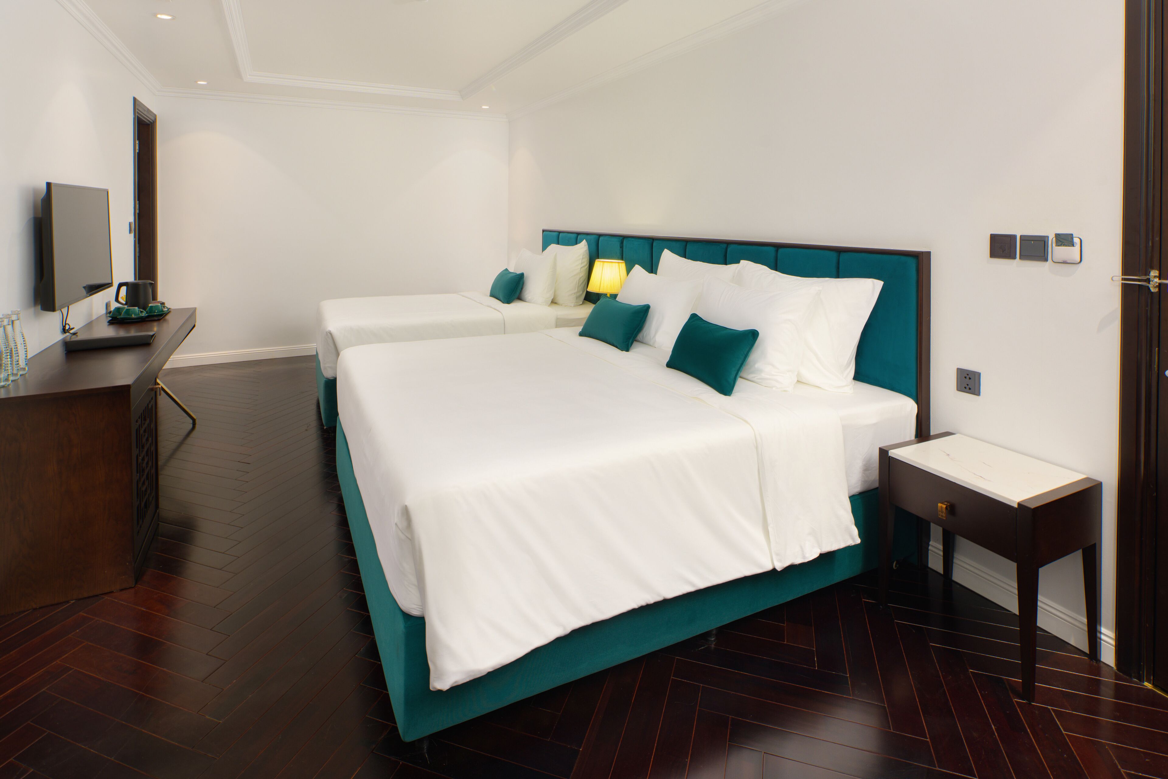Habitación de hotel con una cama grande, una mesita de noche, un televisor y un escritorio con una silla.