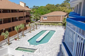 Zona de piscina con una pileta rectangular, rodeada por una cerca blanca y palmeras.