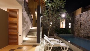 A pool area with lounge chairs, a staircase, and a stone wall. - Villa Ananta - 3 Bedroom (Hikkaduwa)