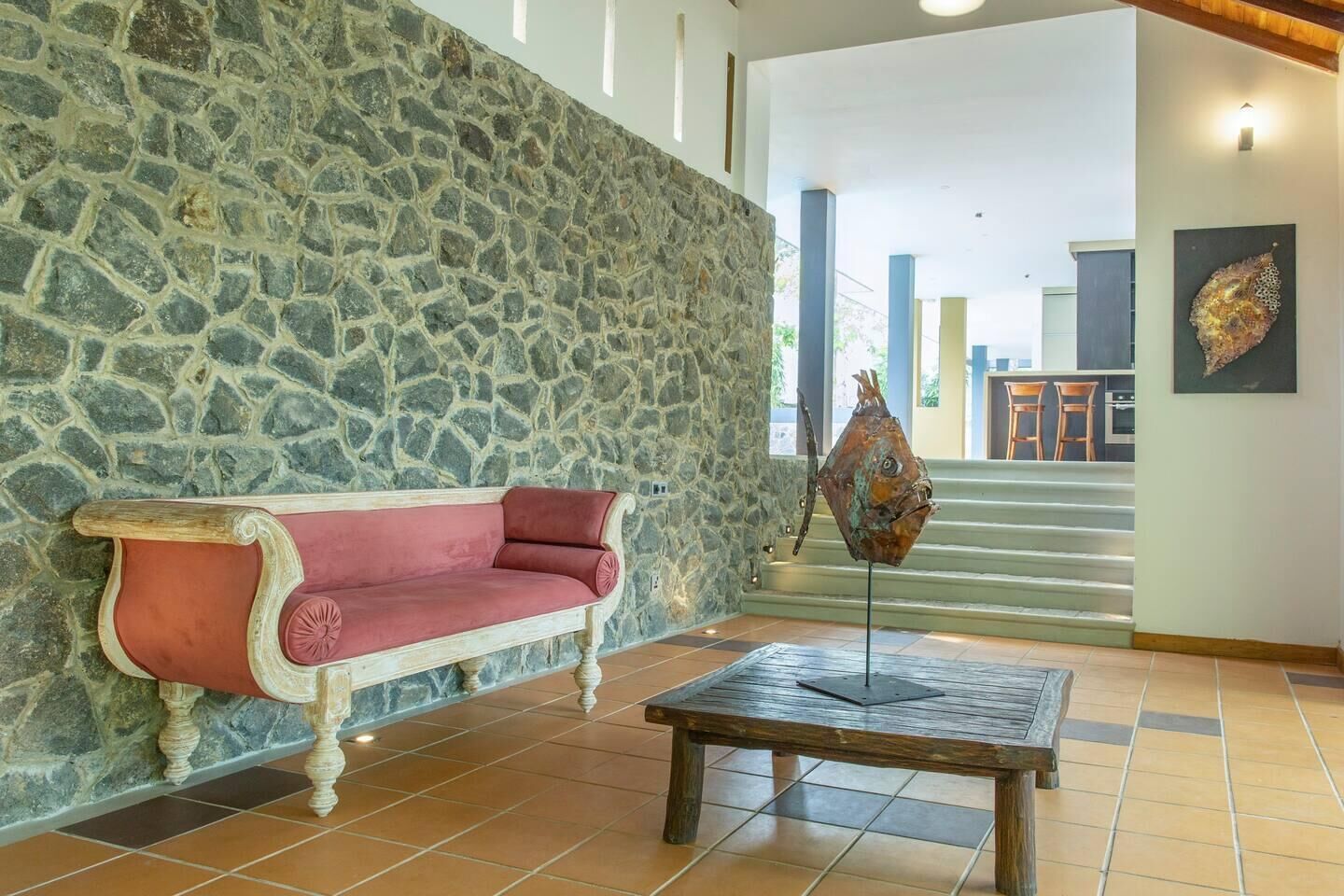 A stone wall, a red sofa, and a metal sculpture in a lobby area.