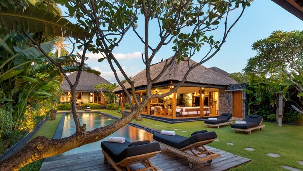 A resort with a pool, lounge chairs, and a thatched-roof building. - Villa Wolfe by Villa Finder (Seminyak)