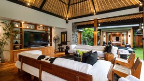 A spacious living area with a large flat-screen TV, comfortable seating, and a thatched ceiling. - Villa Wolfe by Villa Finder (Seminyak)